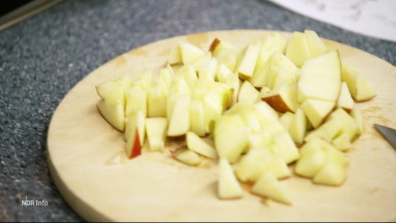 Nahaufnahme von geschnittenem Apfel auf einem Holzbrett. © Screenshot 