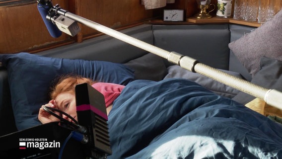 Ein im Bett liegende Frau wird bei Dreharbeiten gefilmt. © Screenshot 