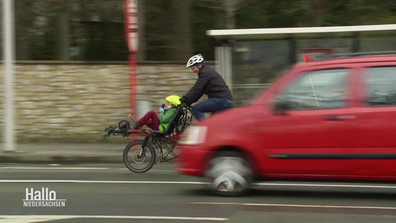 Ein Vater mit seinem Kind auf einem Fahrrad im Straßenverkehr. © Screenshot 