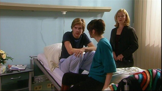 Lars sitzt mit Mara auf seinem Krankenbett. © Screenshot 