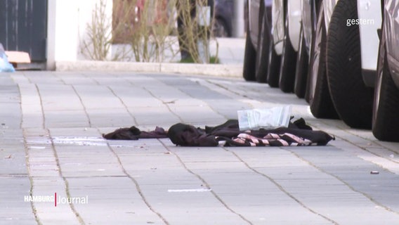 Kleider, die auf einem Fußweg liegen © Screenshot 