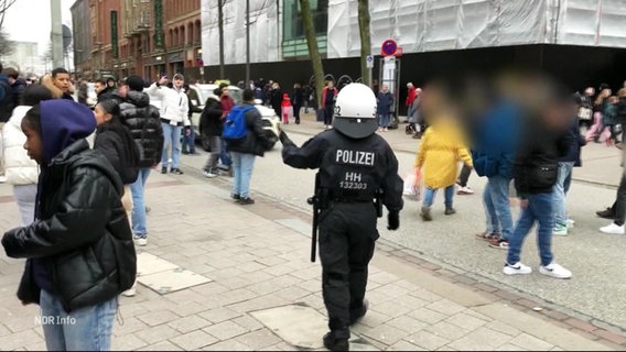 Eine Person in Polizeiuniform auf der Mönckebergstraße vor einer Menge von Menschen © Screenshot 