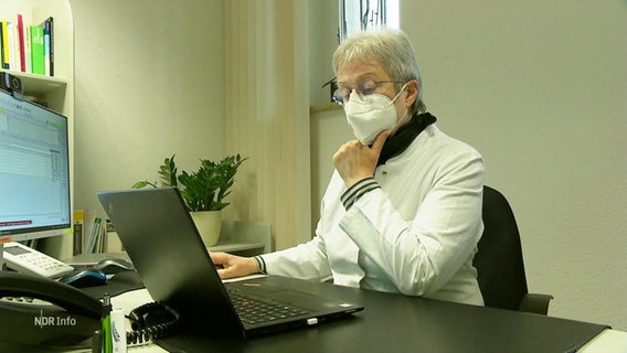 Eine Person in Kittel und mit FFP 2 Maske bedient einen Laptop © Screenshot 