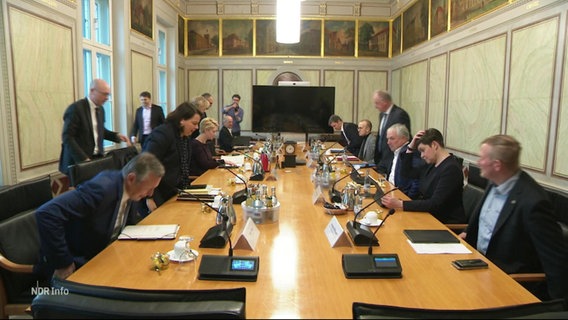Politikerinnen und Politiker setzen sich an einen großen Tisch. © Screenshot 