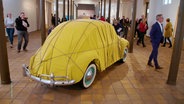 Ausstellung auf Schloss Gottorf: Ein verhüllter VW-Käfer, Kunstwerk der Verhüllungskünstler Christo und Jeanne-Claude. © Screenshot 
