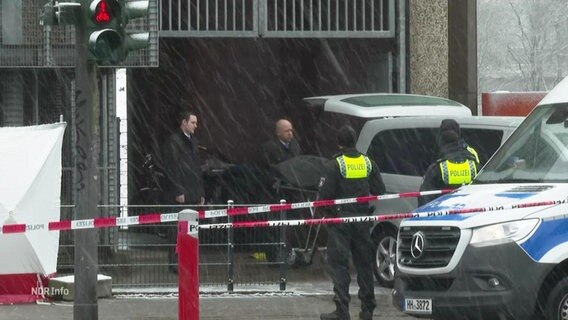 Ein Sarg wird, bewacht von Polizeibeamten, in ein Auto geladen. © Screenshot 