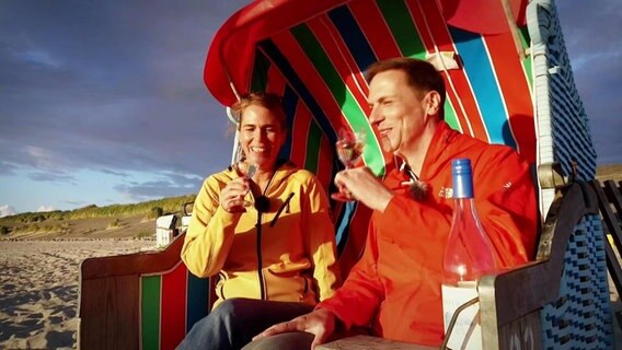 Anne Brüning und Mathias Münch sitzen in einem Strandkorb und trinken Sekt. © Screenshot 