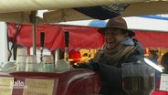 Ein Mann mit Hut bedient eine Kaffeemaschine und lacht. © Screenshot 
