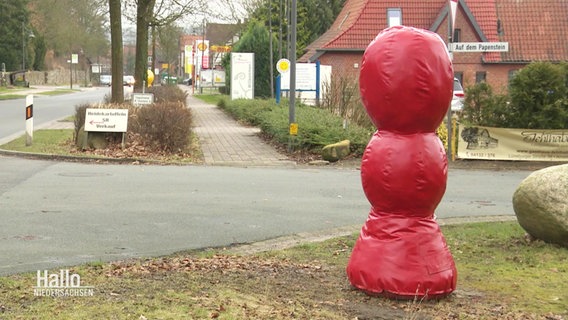 Eine rote Skulptur steht neben einer Straße. © Screenshot 