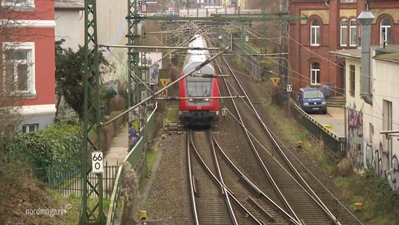 Eine Bahn fährt zwischen Häuserreihen hindurch. © Screenshot 