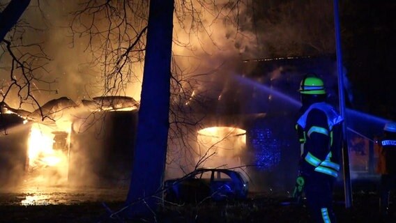 Ein Feuerwehrmann vor einer brennenden Scheune. © Screenshot 