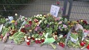 Blumen liegen vor dem Gebetshaus der Zeugen Jehovas auf dem Boden. © Screenshot 