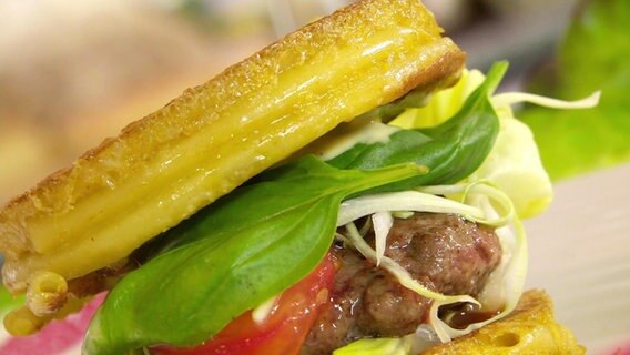 Ein frisch belegter Burger mit Feldsalat und Tomaten © Screenshot 