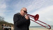 Nils Landgren spielt Posaune am Strand. © Screenshot 