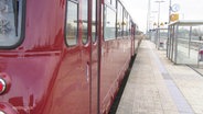 Ein Zug mit roten Waggons steht an einem Bahngleis © Screenshot 