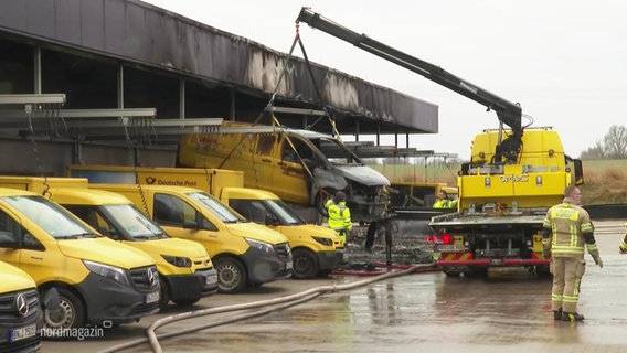 Ein LKW hebt mit einem Kran ein verbranntes Post-Fahrzeug hoch. © Screenshot 