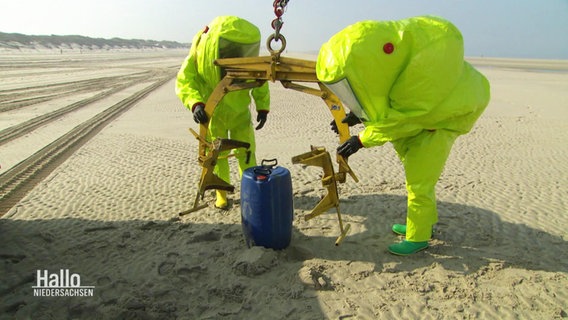 Zwei Menschen in gelben Anzügen am Strand. © Screenshot 