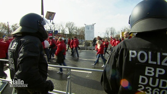 Fußballfans gehen hinter einer Polizeikette. © Screenshot 