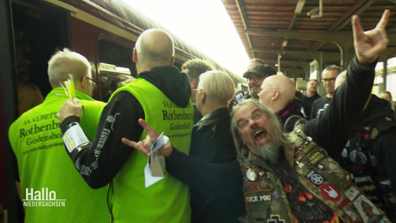 Metal Fans am Bahnhof vor einem Zug. © Screenshot 