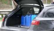 Ein schwarzer Audi, im Kofferraum drei blaue Kannister. © Screenshot 