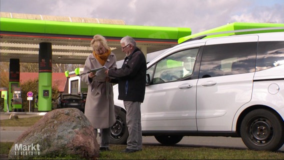 Zwei Personen an einer Tankstelle vor einem Auto © Screenshot 