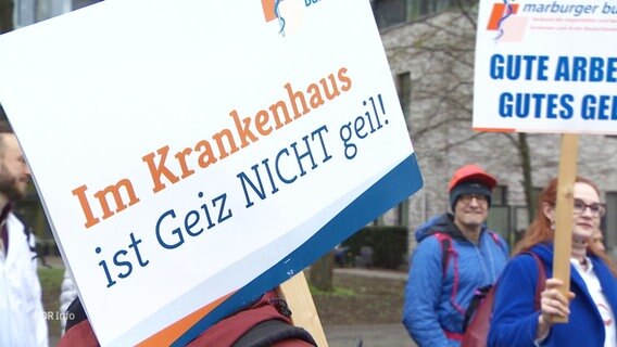 Protestierende halten ein Schild mit der Aufschrift: "Im Krankenhaus ist Geiz NICHT geil!" © Screenshot 