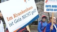 Protestierende halten ein Schild mit der Aufschrift: "Im Krankenhaus ist Geiz NICHT geil!" © Screenshot 