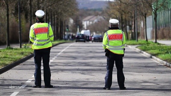 Zwei Polizeibeamte sperren eine Straße © Screenshot 