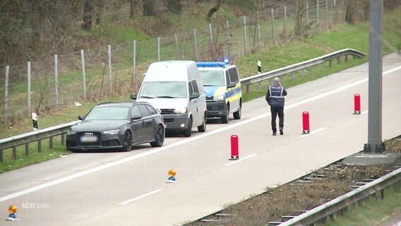 Ein Polizist steht mit einigen Autos an der Seite einer Fahrbahn © Screenshot 