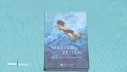 Das Buch "Wasserzeiten" vor dem Hintergrund einer türkisblauen Wasseroberfläche. © Screenshot 