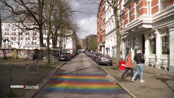 Zwei Menschen überqueren eine Staße in St Georg, auf der ein Regenbogen gemalt ist. © Screenshot 