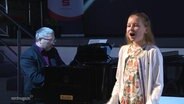Ein Pianist und ein singendes Mädchen auf einer Bühne © Screenshot 