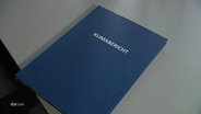 Ein Buch mit der Aufschrift "Klimabericht" liegt auf einem Tisch. © Screenshot 