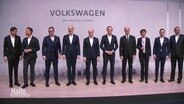 Vorstandsmitglieder von VW stehen auf einer Bühne © Screenshot 