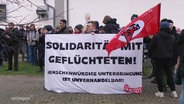Demonstrierende Menschen halten ein Banner mit der Aufschrift:"Solidarität mit Geflüchteten!" © Screenshot 