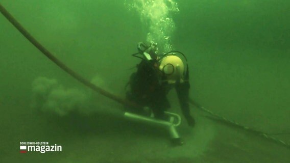 Ein Taucher sucht den Meeresboden nach Altlasten ab. © Screenshot 