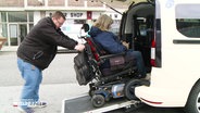 Ein Taxifahrer hilft einer Frau im Rollstuhl aus einem Taxi © Screenshot 