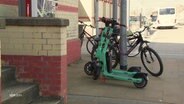 Zwei E-Roller stehen abgestellt auf einem Gehweg neben einem Fahrrad. © Screenshot 