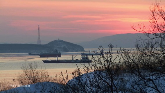 Containerschiffe auf einem Fluss bei Abendrot und verschneiter Landschaft bei Wladiwostok. © Screenshot 