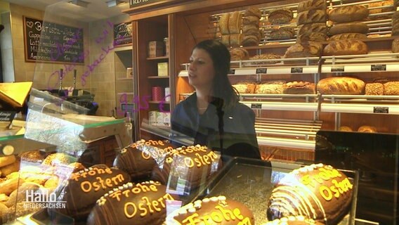 Eine Bäckerin hinter ihrer Ladentheke, Backwaren im Vordergrund. © Screenshot 