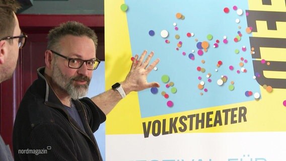 Ralph Reichel, Intendant des Volkstheaters Rostock, vor einem Plakat zum Theatersommer. © Screenshot 