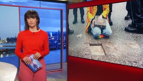 Theresa Pöhls moderiert die Frühausgabe Hamburg Journal. Im Hintergrund ist ein Foto einer Klimaaktivistin der Gruppe "Die Letzte Generation", die sich ihre Hand an eine Straße geklebt hat zu sehen. © Screenshot 