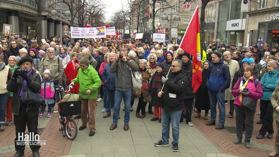 Viele Menschen stehen zusammen und hören einer Kundgebung zu. © Screenshot 