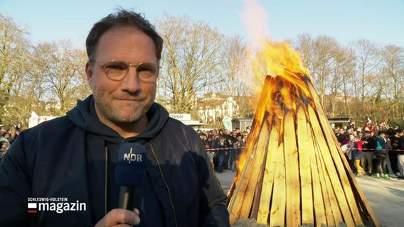 Reporter Jochen Dominicus steht vor einem brennenden Osterfeuer. © Screenshot 