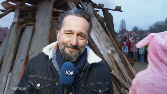 Reporter Stefan Weidig steht mit einem Mikro vor einem Osterfeuer. © Screenshot 