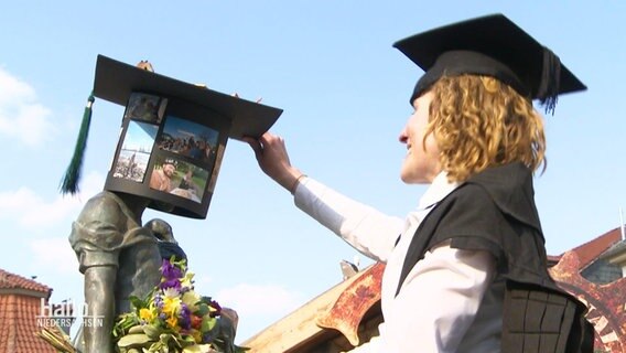 Doktorandin steckt Blumen und Hut an die Gänselisel. © Screenshot 