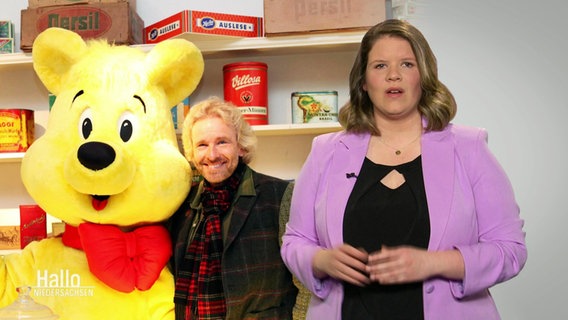 Eine NDR-Journalistin trägt Argumente für die Werbefreiheit von Süßwaren vor. Im Hintergrund Thomas Gottschalk neben einem riesigen Goldbären. © Screenshot 