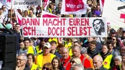 Demonstration für bessere Arbeitsbedingungen. Auf einem Transparent steht: "Dann macht Euren Scheiß doch selbst!" © Screenshot 