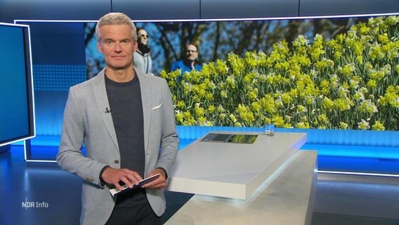 Moderator Thorsten Schröder, im Hintergrund ein Bild von einem Blumenbeet. © Screenshot 