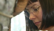 Nahaufnahme: Eine junge Frau mit Brille blickt vor sich konzentriert hinunter. © Screenshot 